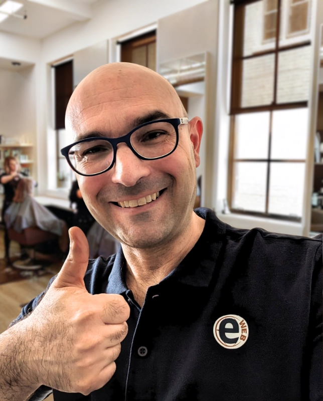 Foto profilo di Salvatore web designer di Pistoia con un salone di parrucchiere sfocato sullo sfondo